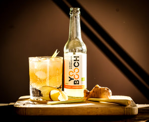 Produktfoto einer Flasche YO BOOCH Craft Kombucha ginger lemongrass mit einem Glas, Ingwer und Zitronengras
